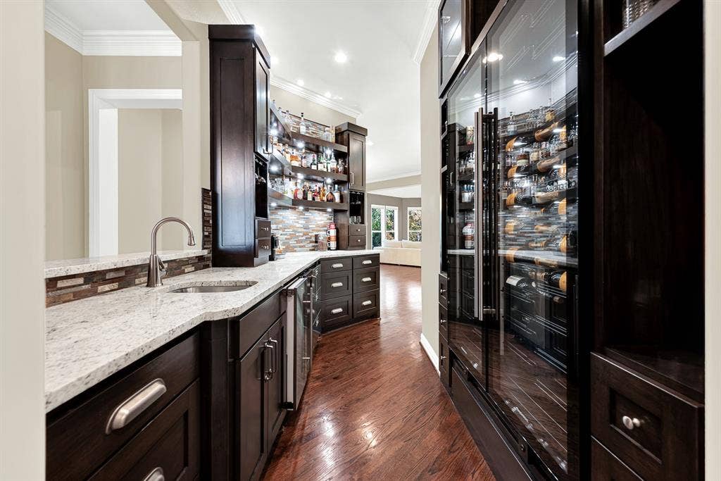 5237 SKY LAKE Drive, Plano, TX 75093 Floor-to-ceiling glass display fridges glowing with warm interior lighting anchor this custom passage. Pour a favorite vintage after work as soft light reflects off dark polished millwork