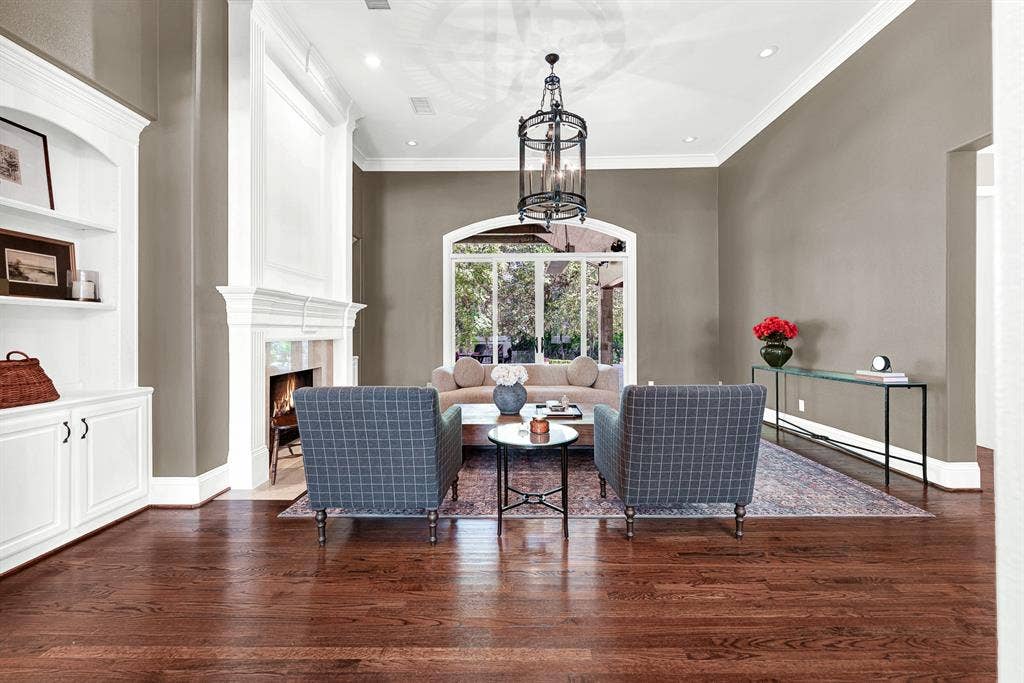 5237 SKY LAKE Drive, Plano, TX 75093 An grand floor-to-ceiling hearth mantle centers the room, framing bright outdoor light filtered through an arched patio wall. Picture yourself unwinding by a roaring fire while soft afternoon sun settles across the warm hardwood floors.
