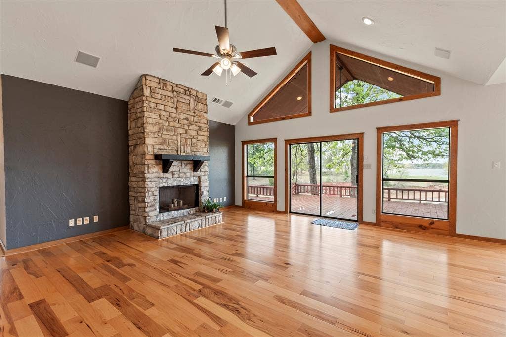 5459 Woodland Shores Drive, Log Cabin, TX 75148 Open living area with vaulted ceilings and stone fireplace. Beautiful Bellawood Engineered Hickory flooring.