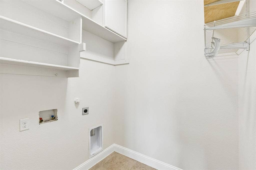 White cabinetry with built-in shelving, tile flooring, and utility hookups