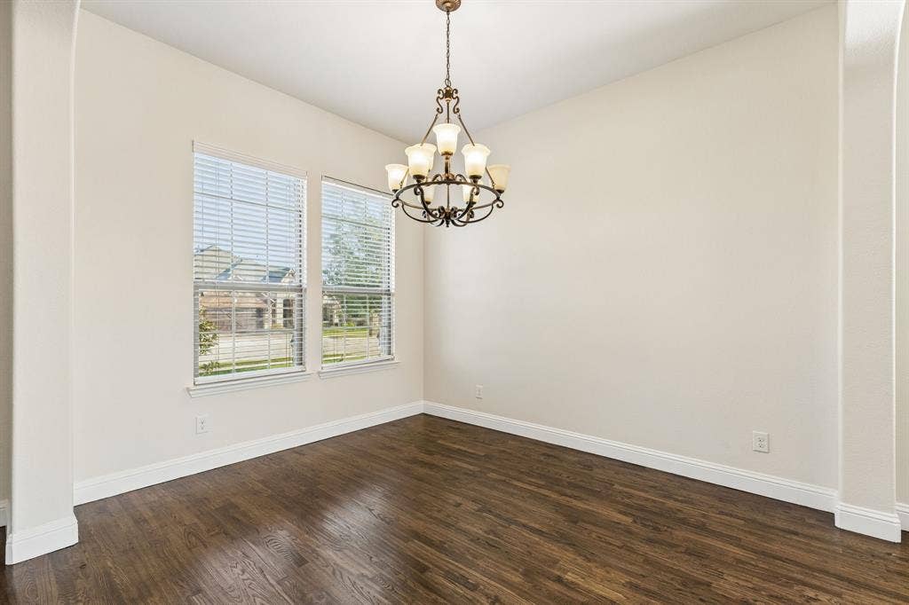 Wood-finish flooring, dual windows with blinds, recessed chandelier, and arched entryway
