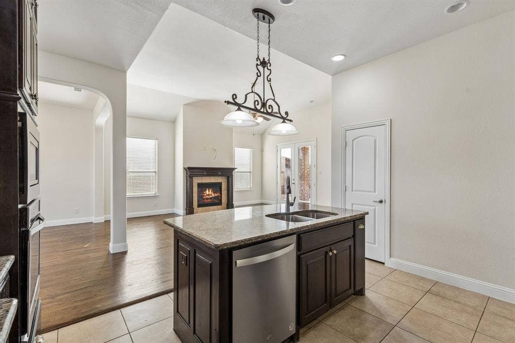 Kitchen island with granite countertop, double basin sink, and integrated stainless steel dishwasher