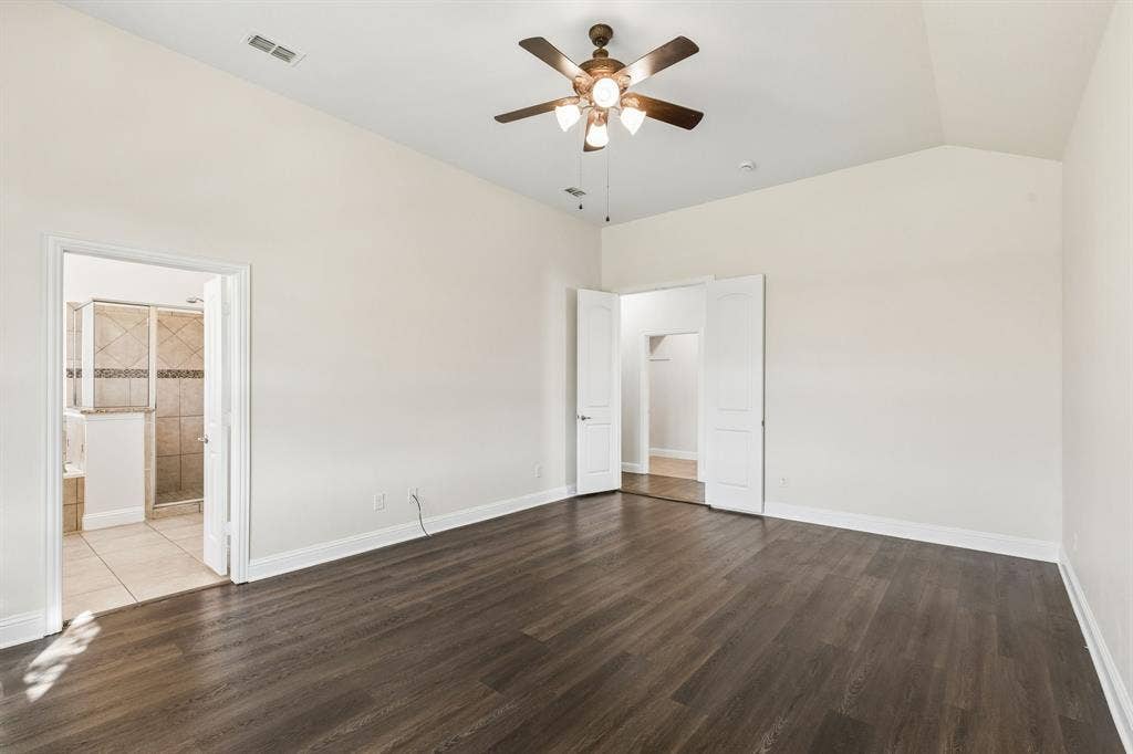 Vaulted ceiling with a ceiling fan, wood-finish flooring, and crisp white walls