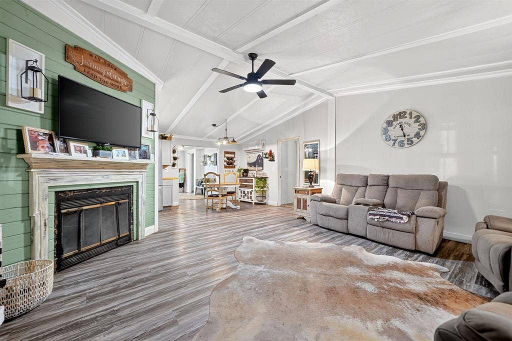 302 Longleaf Street, Gun Barrel City, TX 75156 Living area featuring vaulted ceilings, wood-finish flooring, a decorative fireplace with a mantel, and a ceiling fan