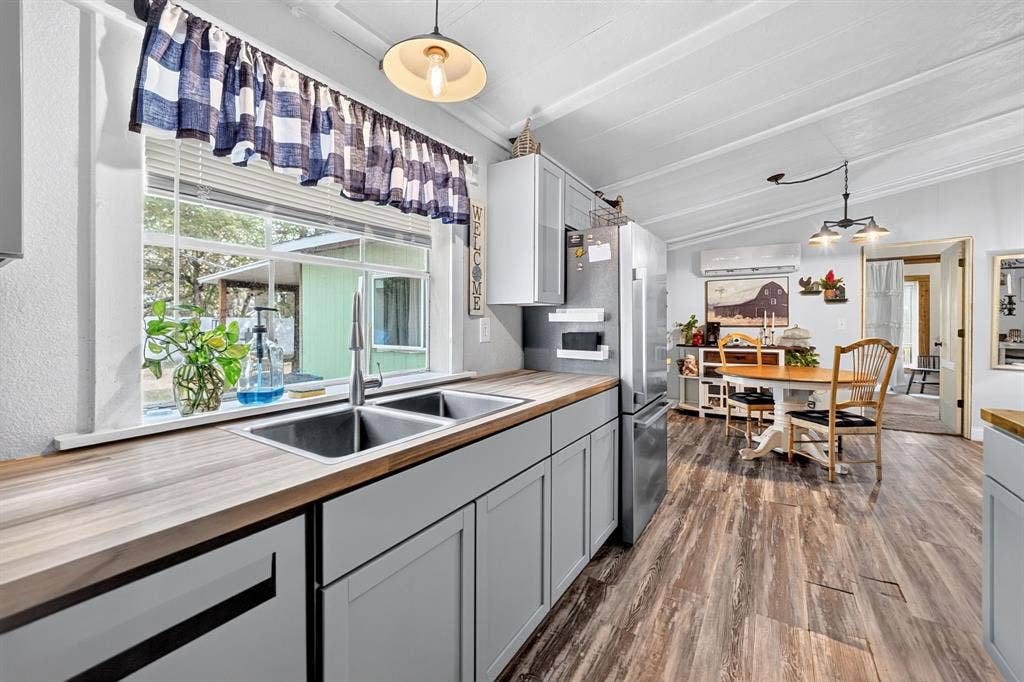 302 Longleaf Street, Gun Barrel City, TX 75156 Kitchen featuring wood-finish countertops, stainless steel double basin sink with a gooseneck faucet, light gray cabinetry, and wood-finish flooring