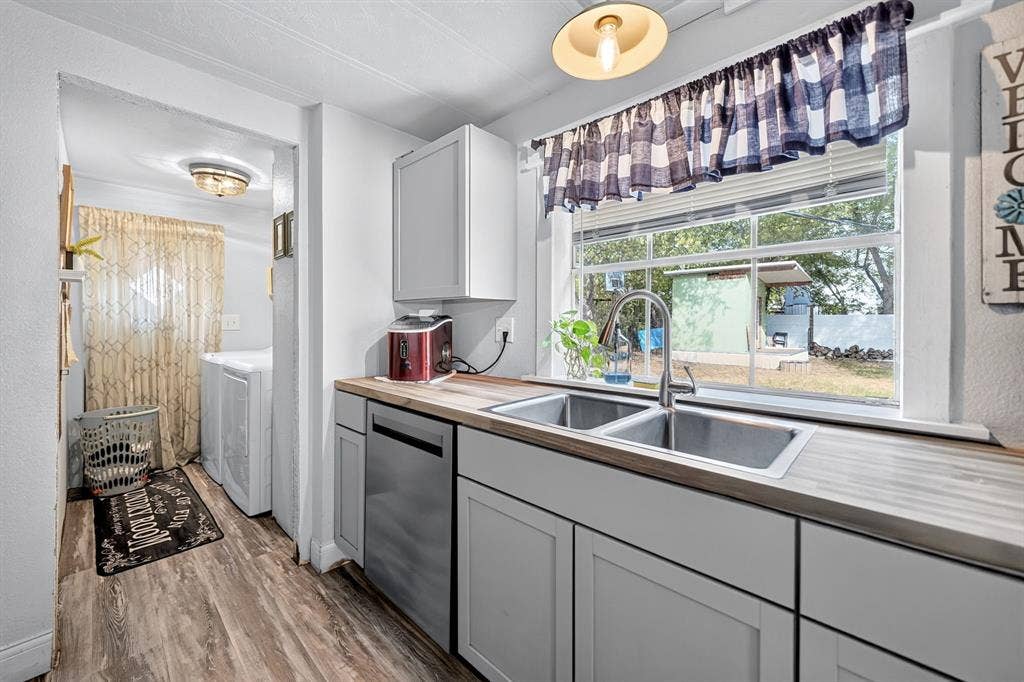 302 Longleaf Street, Gun Barrel City, TX 75156 Dual basin stainless steel sink with a high-arc faucet, wood-finish countertops, and light gray cabinetry