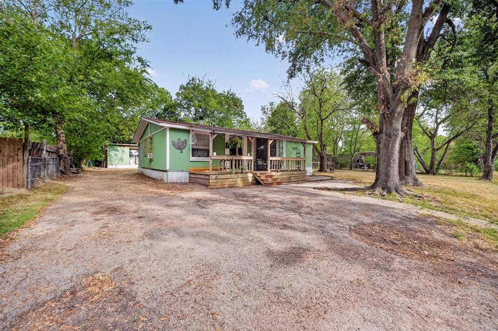 302 Longleaf Street, Gun Barrel City, TX 75156 Green exterior with a covered porch, wood deck, and expansive gravel driveway