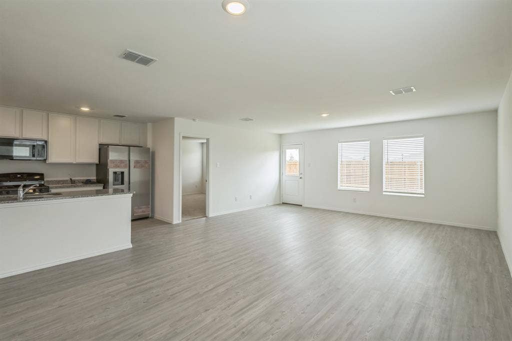 7904 Thornton Drive, McKinney, TX 75071 Open-concept kitchen and living area featuring wood-finish flooring, recessed lighting, white cabinetry, and stainless steel appliances