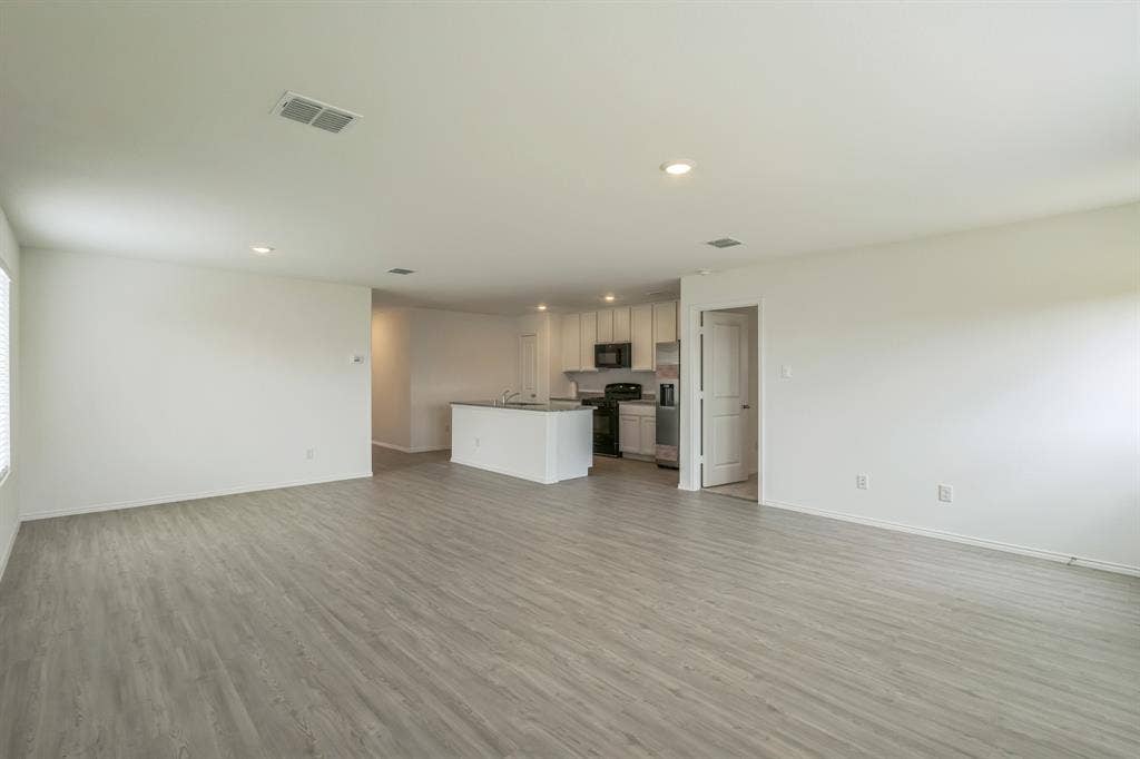 7904 Thornton Drive, McKinney, TX 75071 Open-concept living area featuring wood-finish flooring, recessed lighting, and a kitchen with an island, light-colored cabinetry, and black appliances