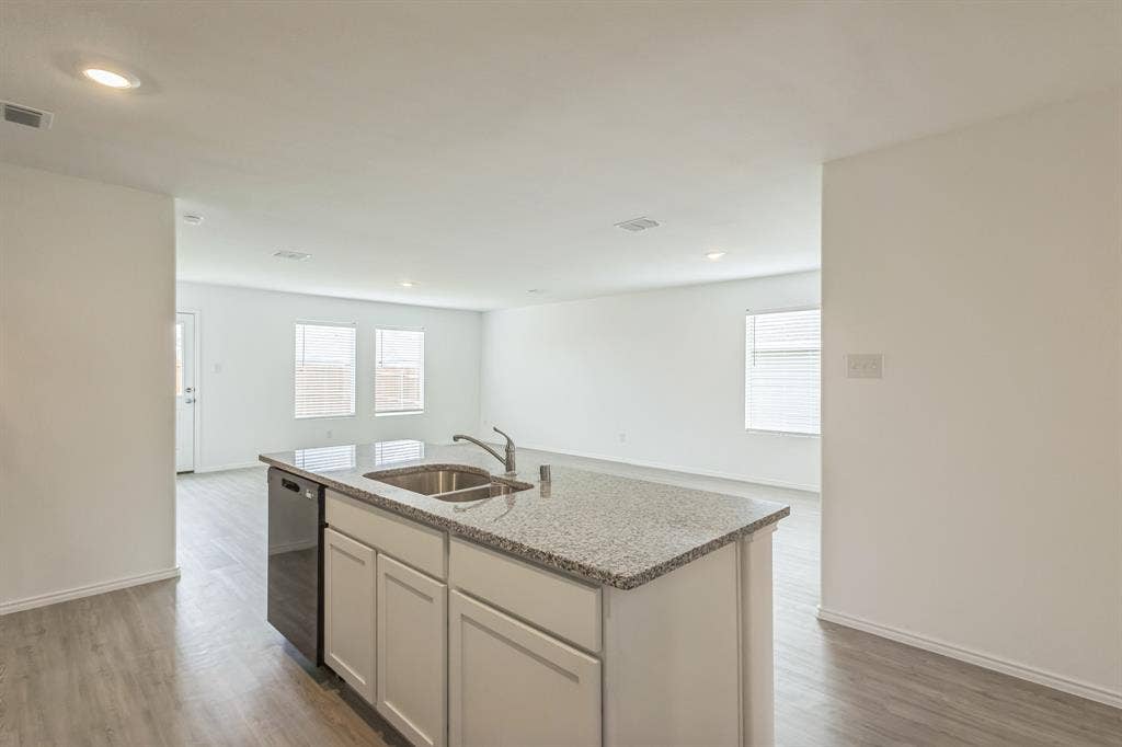 7904 Thornton Drive, McKinney, TX 75071 Kitchen island with a double basin sink, chrome faucet, and stone countertop