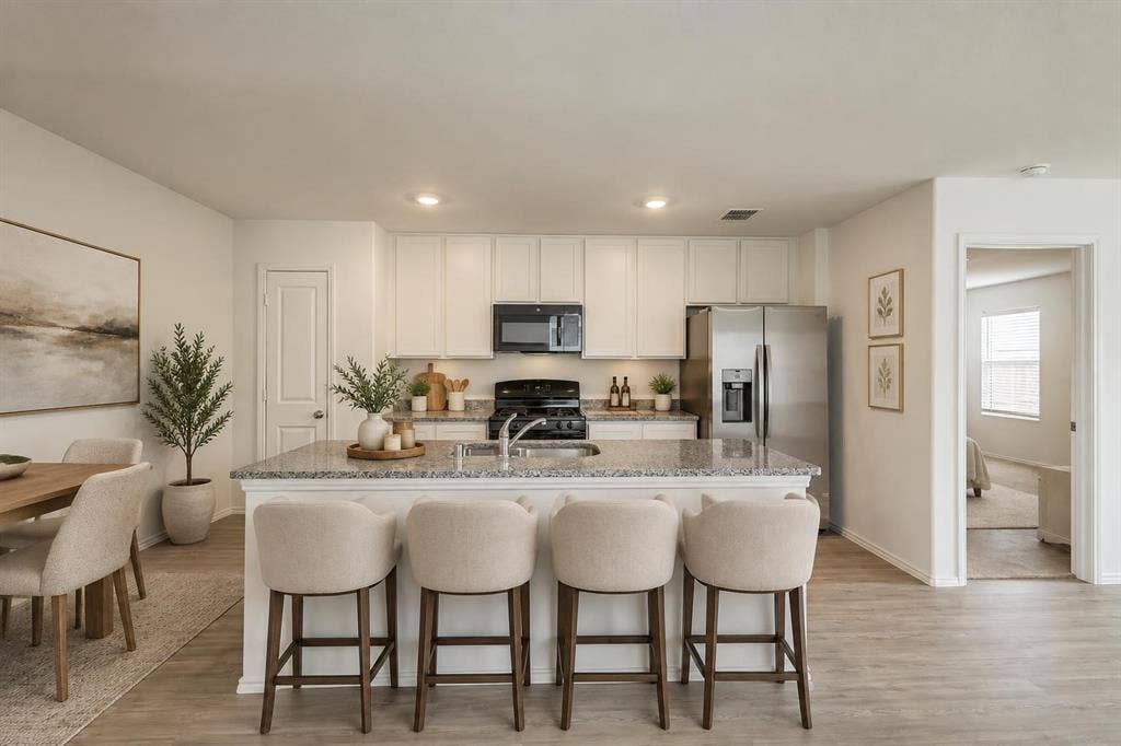 7904 Thornton Drive, McKinney, TX 75071 Kitchen featuring an island with stone countertop, white cabinetry, stainless steel appliances, and wood-finish flooring