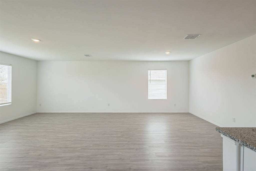 7904 Thornton Drive, McKinney, TX 75071 Spacious room with light wood-finish flooring, recessed lighting, multiple windows with blinds, and white walls