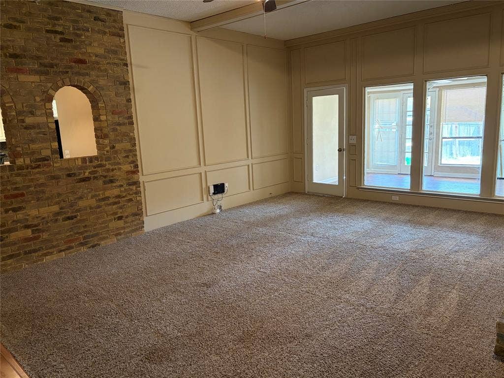3912 Bandera Drive, Plano, TX 75074 Brick accent wall with arched pass-through, paneled walls, and plush carpeting