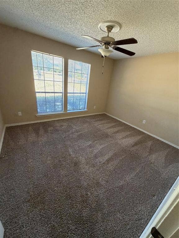 3912 Bandera Drive, Plano, TX 75074 Spacious room featuring neutral carpeting, two large windows with blinds, a ceiling fan with integrated lighting, and textured ceilings