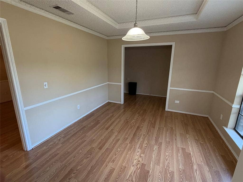 3912 Bandera Drive, Plano, TX 75074 Wood-finish flooring, two-tone wall treatment with chair rail, recessed ceiling detail, and a white dome pendant light fixture