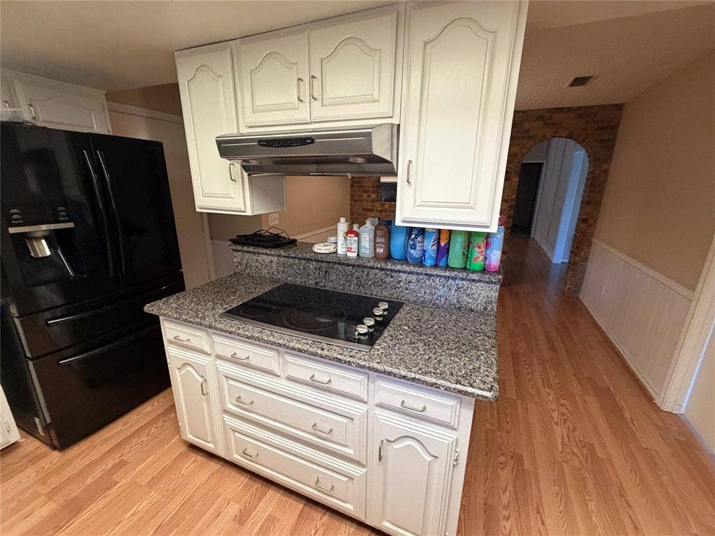 3912 Bandera Drive, Plano, TX 75074 Kitchen island with built-in electric cooktop, white cabinetry, and a granite-finish countertop