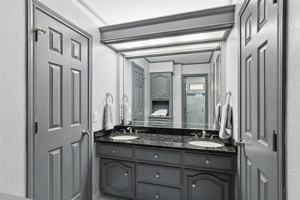 5716 Plumtree Drive, Dallas, TX 75252 Dual basin vanity with a dark stone countertop