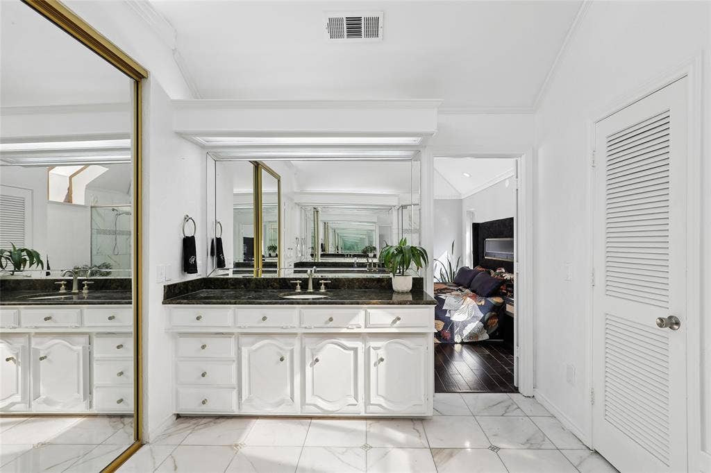 5716 Plumtree Drive, Dallas, TX 75252 Dual vanity with dark stone countertop, white cabinetry, and wall-mounted mirrors