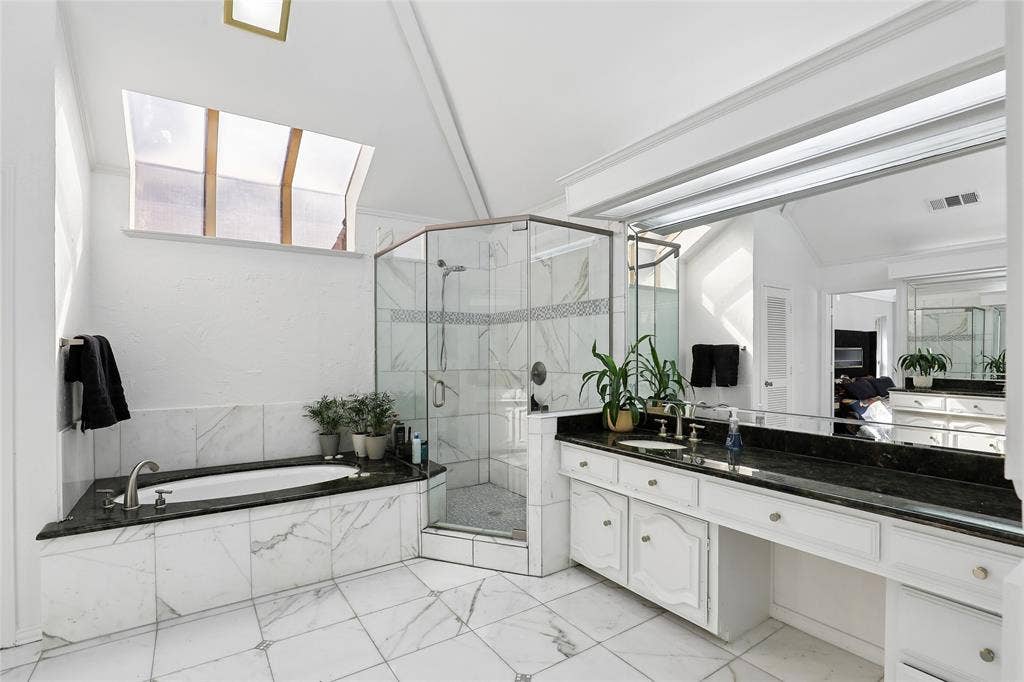 5716 Plumtree Drive, Dallas, TX 75252 Just stunning! Vaulted ceiling with skylight, marble tiled flooring, built-in soaking tub with dark countertop, glass-enclosed shower, and dual vanity with dark granite countertops