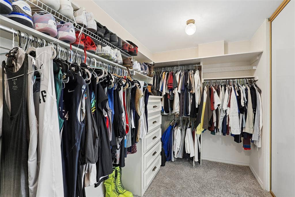 5716 Plumtree Drive, Dallas, TX 75252 Luxury walk-in closet featuring built-in shelving, multiple hanging rods, integrated drawer storage, and carpet flooring