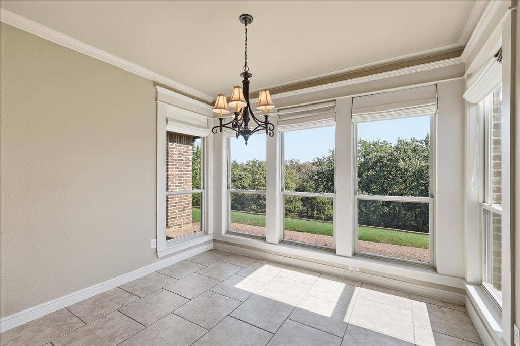 3110 Creek Haven Drive, Highland Village, TX 75077 Natural light-filled room featuring large windows with window treatments, neutral stone-finish tile flooring, crown molding, and an intricate dark metal multi-arm chandelier