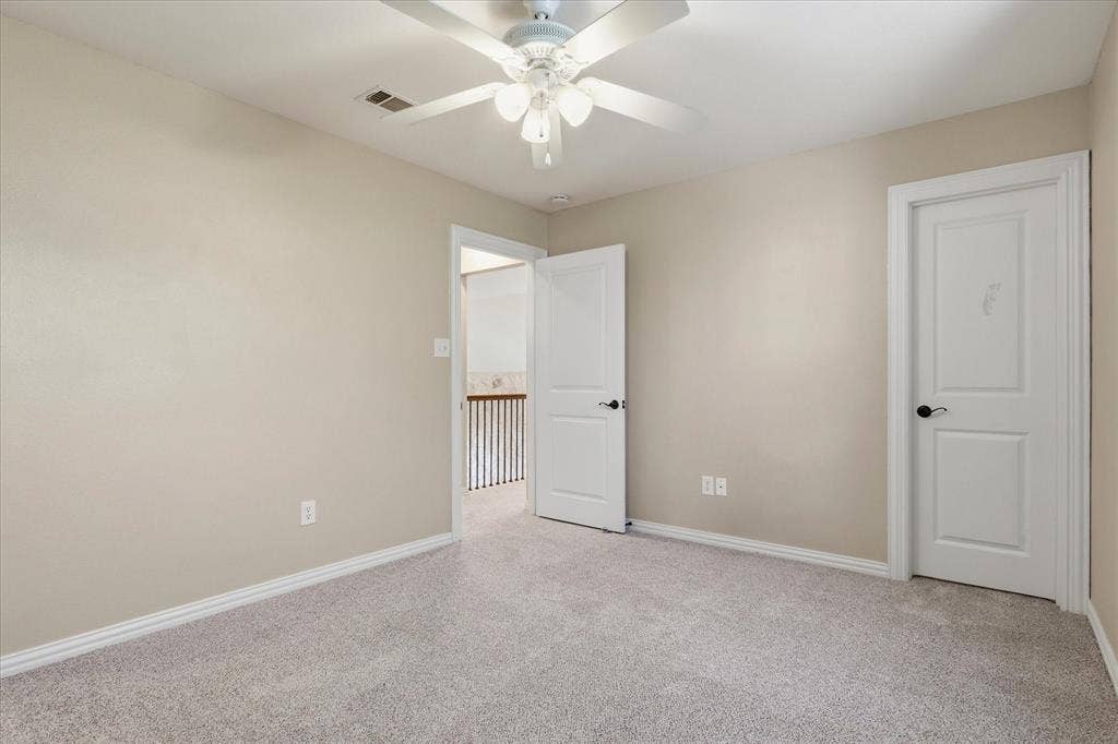 3110 Creek Haven Drive, Highland Village, TX 75077 Neutral wall tones, wall-to-wall carpeting, white interior doors with matte black hardware, and a ceiling-mounted light fixture with a fan