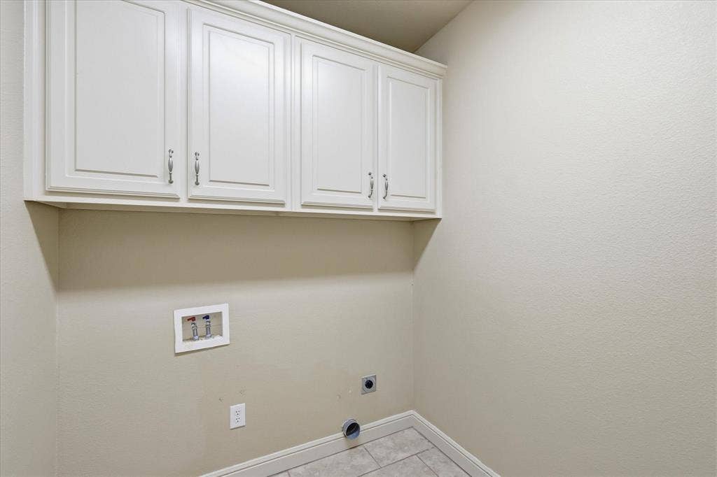 3110 Creek Haven Drive, Highland Village, TX 75077 Utility space featuring wall-mounted white cabinetry with shaker-style doors, tile flooring, and dedicated plumbing connections