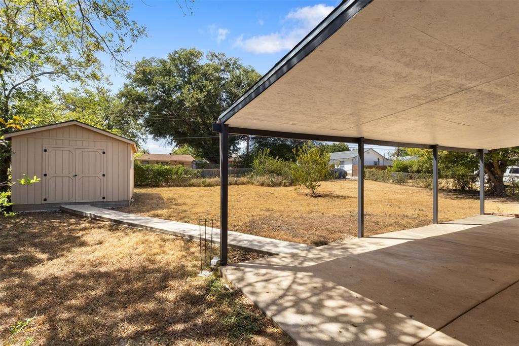 2563 Wood Valley Drive, Dallas, TX 75211 Expansive backyard featuring a covered patio, concrete walkway, and a detached storage shed
