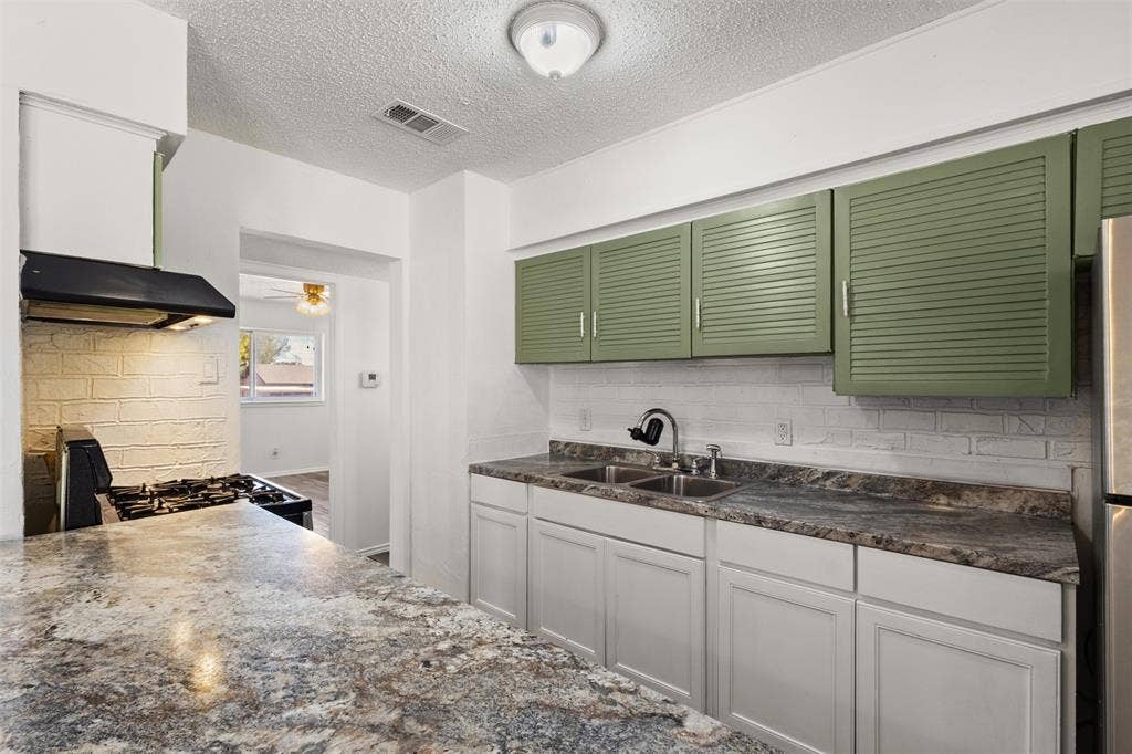 2563 Wood Valley Drive, Dallas, TX 75211 Kitchen featuring light green upper cabinetry, white lower cabinetry, and a double basin stainless steel sink
