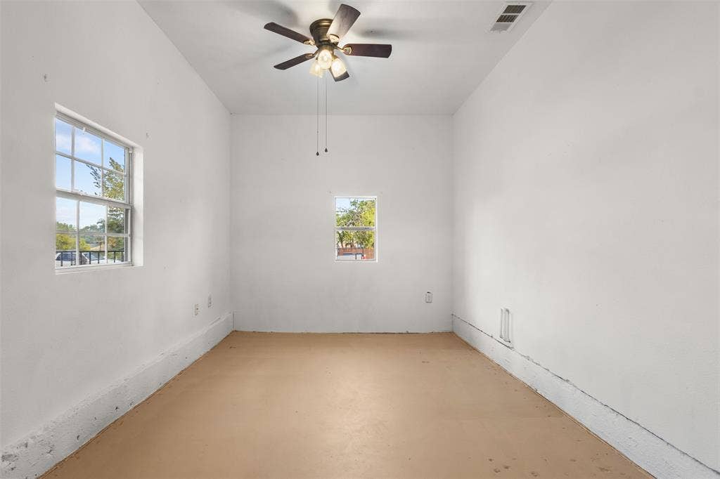 2563 Wood Valley Drive, Dallas, TX 75211 White painted walls, two windows providing natural light, ceiling fan with integrated lighting, and a neutral-toned floor