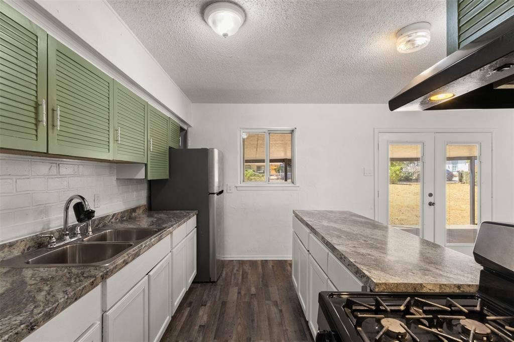 2563 Wood Valley Drive, Dallas, TX 75211 Kitchen featuring a dual basin sink, white cabinetry, wood-finish flooring, a center island with a countertop, and double glass doors leading to the exterior
