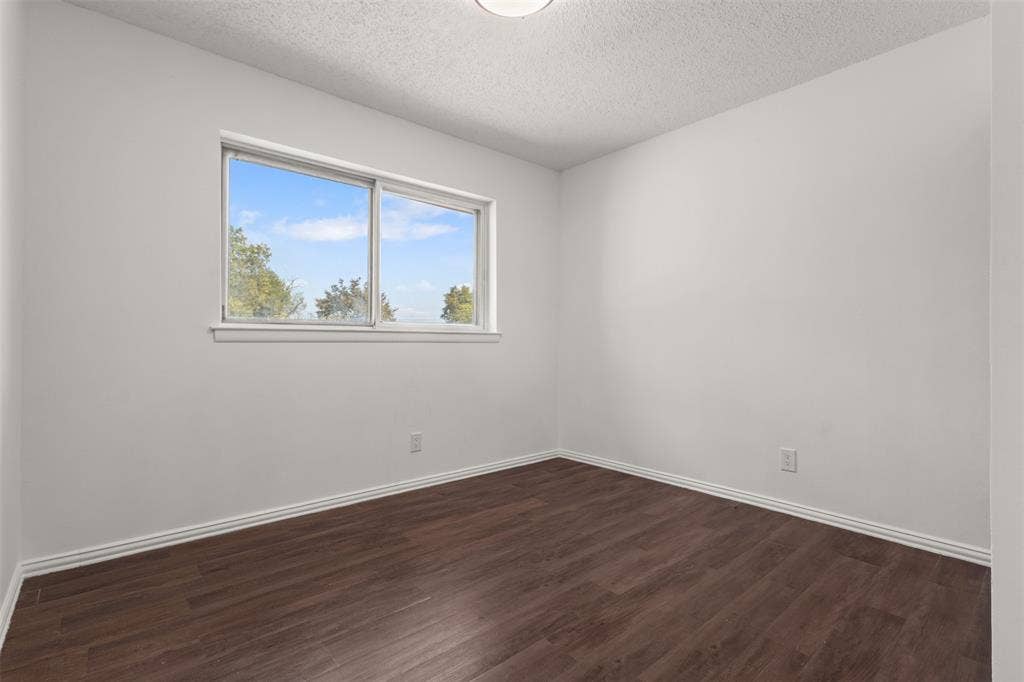 2563 Wood Valley Drive, Dallas, TX 75211 Interior room featuring a large window, dark wood-finish flooring, and white walls