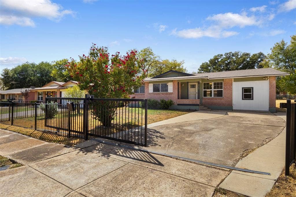 2563 Wood Valley Drive, Dallas, TX 75211 Brick exterior with a partial white facade, a multi-pane window, and a concrete driveway