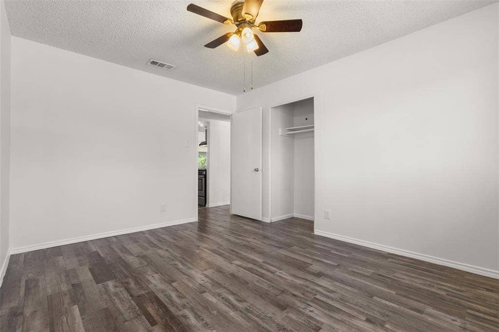 2563 Wood Valley Drive, Dallas, TX 75211 Wood-finish flooring, ceiling fan with integrated lighting, recessed clothing rod, and white walls
