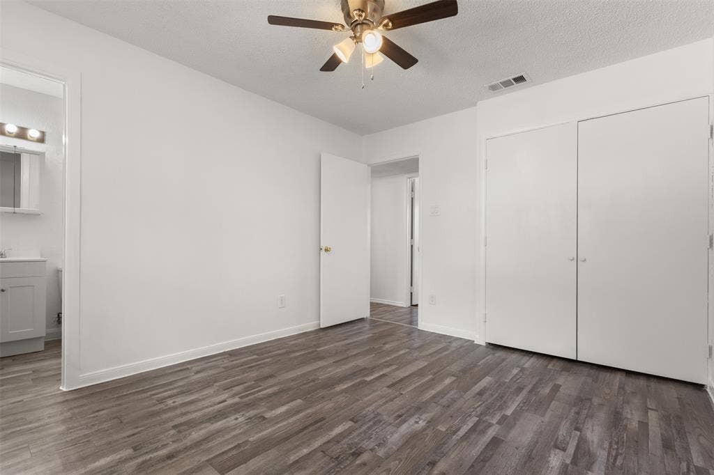 2563 Wood Valley Drive, Dallas, TX 75211 Wood-finish flooring, ceiling fan with light fixture, built-in closet with double doors, and a vanity with a mirror and light bar