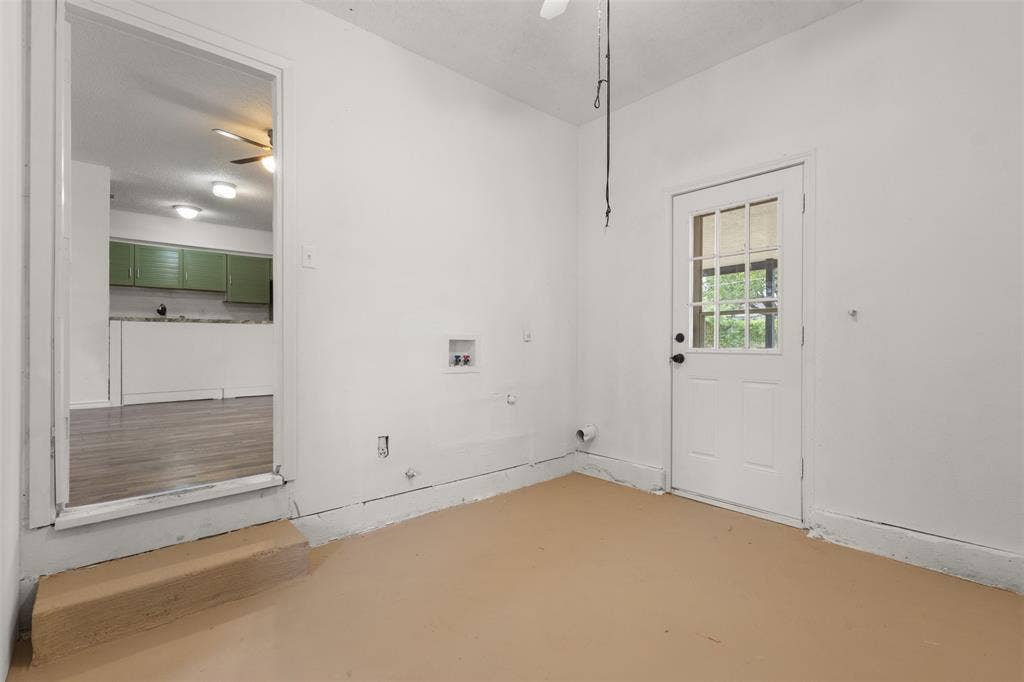 2563 Wood Valley Drive, Dallas, TX 75211 Utility room featuring a paneled door with glass inserts, dedicated laundry hookups, and a neutral-toned floor