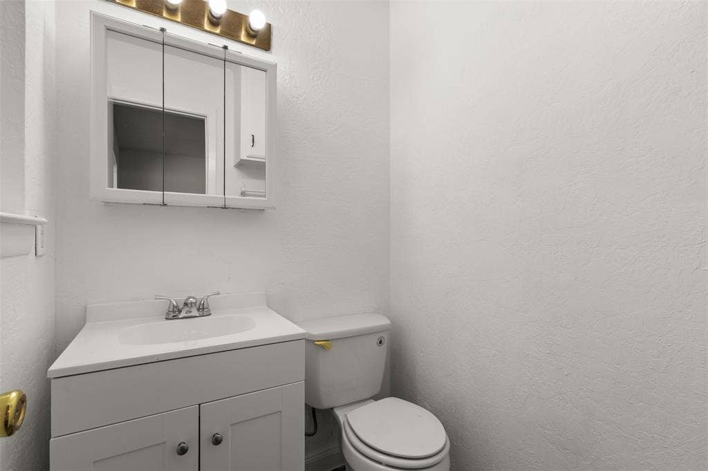 2563 Wood Valley Drive, Dallas, TX 75211 White vanity with double-door cabinetry, integrated sink, and chrome-finish faucet