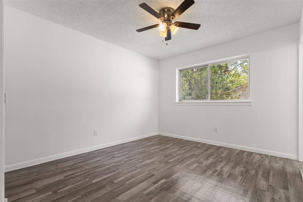 2563 Wood Valley Drive, Dallas, TX 75211 Wood-finish flooring, white walls, window, and ceiling fan with integrated lighting