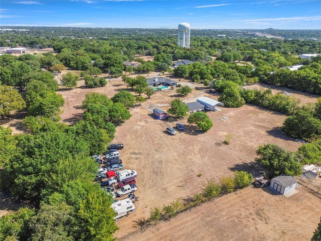 1022 Sherman Drive, Cedar Hill, TX 75104 Expansive property with mature trees, a detached storage building, and a water tower structure in the background