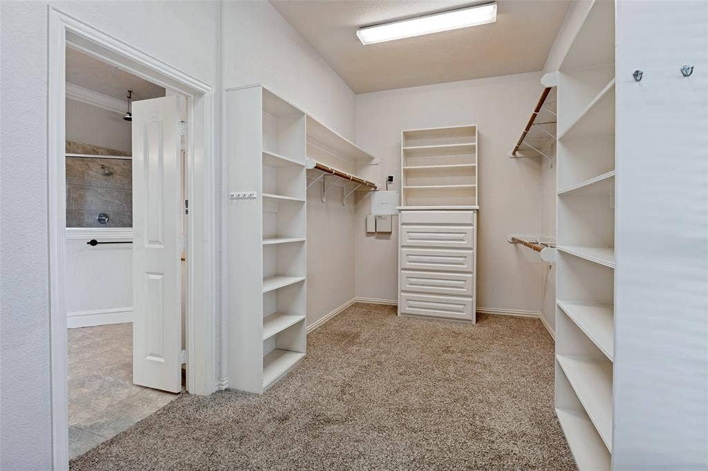 806 Cobblestone Court, Cedar Hill, TX 75104 Walk-in closet featuring carpet flooring, built-in shelving, hanging rods, and a dresser with integrated shelving