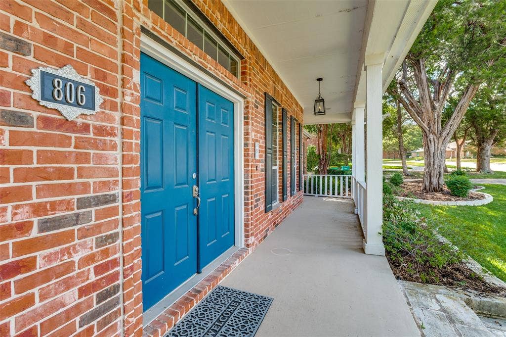806 Cobblestone Court, Cedar Hill, TX 75104 Brick exterior with a covered porch, blue double entry doors, transom window, and decorative house numbers