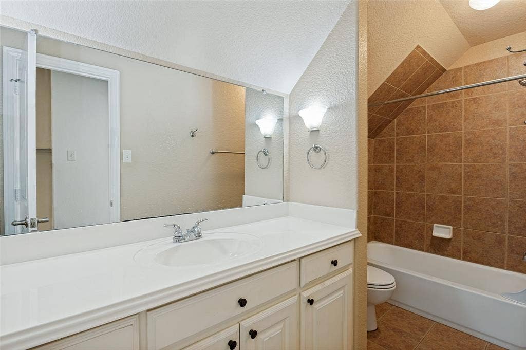806 Cobblestone Court, Cedar Hill, TX 75104 White vanity with integrated sink, chrome faucet, wall-mounted sconces, and a large mirror