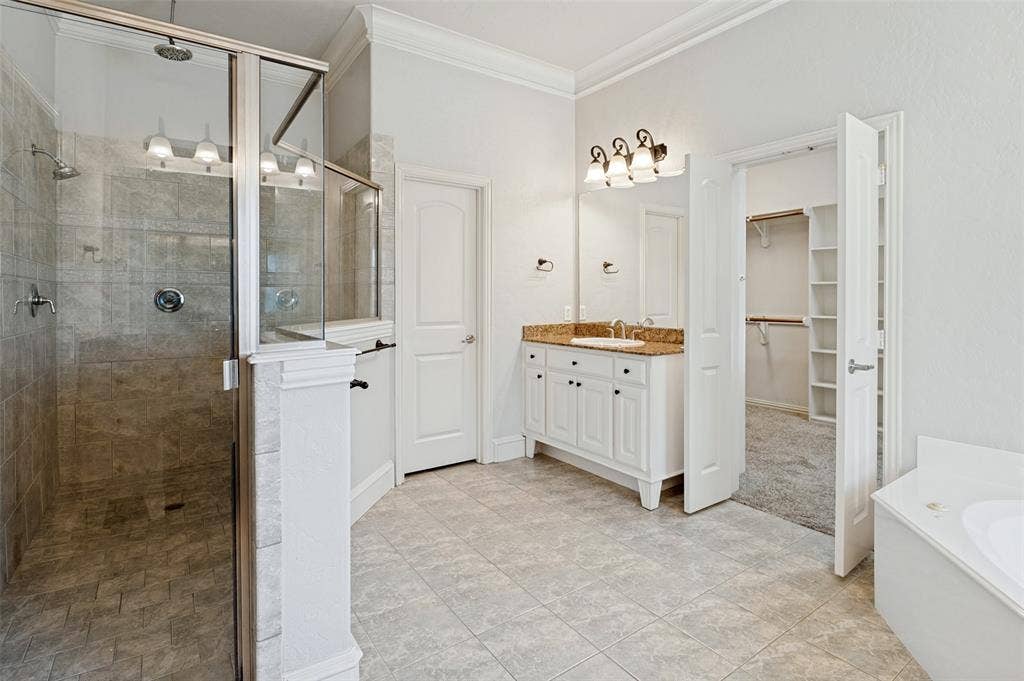 806 Cobblestone Court, Cedar Hill, TX 75104 Glass-enclosed shower with tile surround, double vanity with stone countertop, tile flooring, and separate closet access