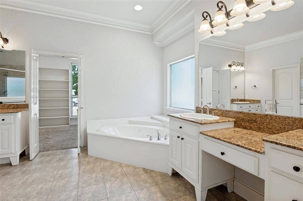806 Cobblestone Court, Cedar Hill, TX 75104 Bathroom featuring dual vanities with stone countertops, a built-in corner soaking tub, tile flooring, and crown molding