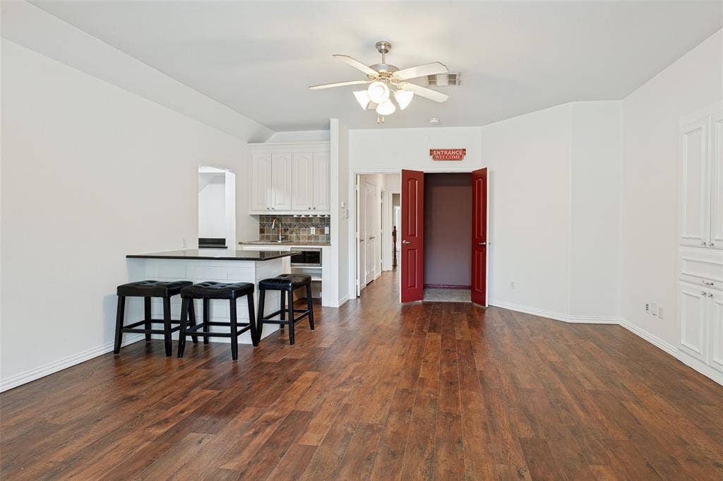 806 Cobblestone Court, Cedar Hill, TX 75104 Wood-finish flooring, white cabinetry, island with countertop, ceiling fan, and built-in storage