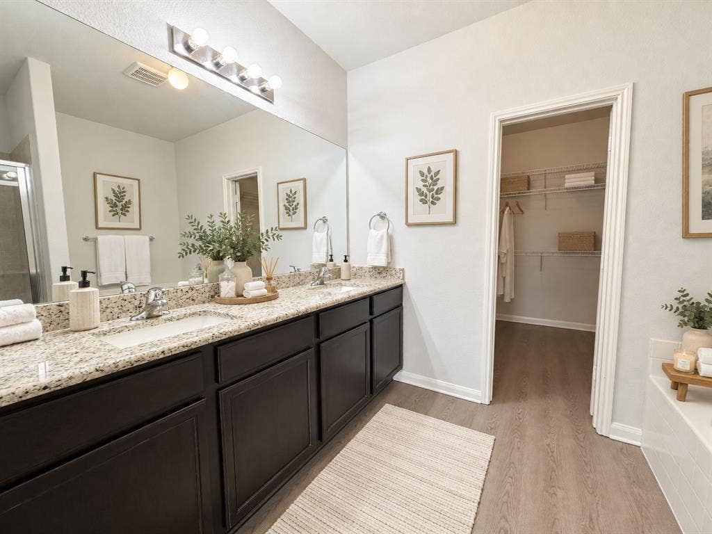 Dual vanity with granite-style countertops, dark wood-finish cabinetry, and undermount sinks