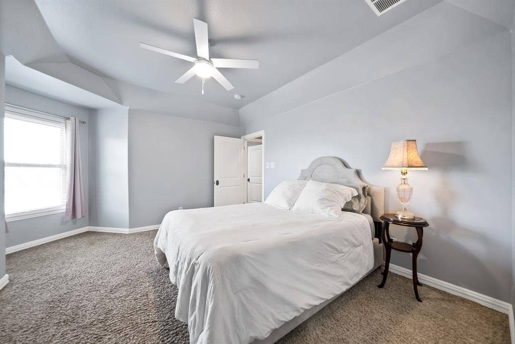 Tray ceiling with a ceiling fan, carpeted flooring, window with blinds, and white doors