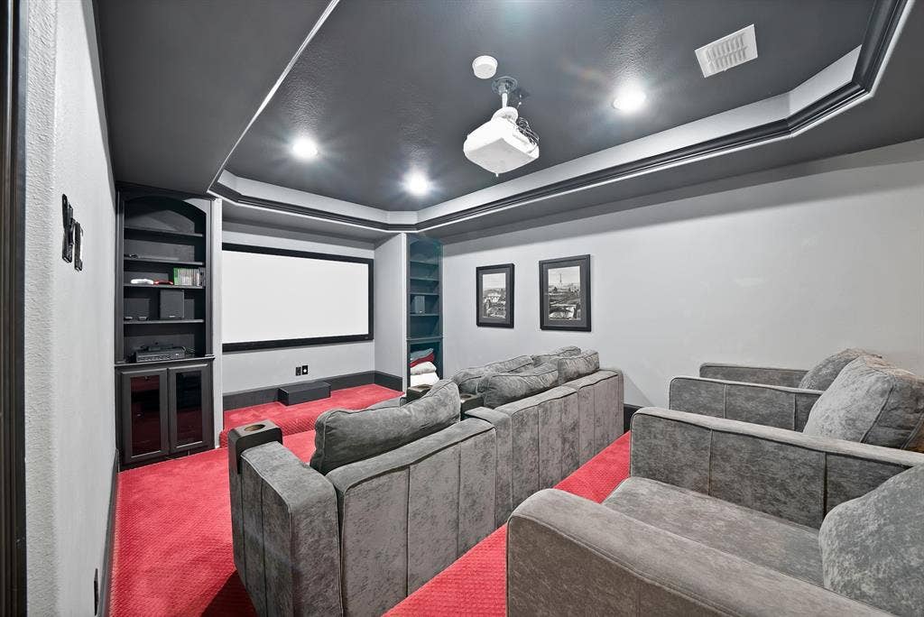 Theater room featuring a projection screen, built-in shelving, recessed lighting, and a dark-painted ceiling with crown molding