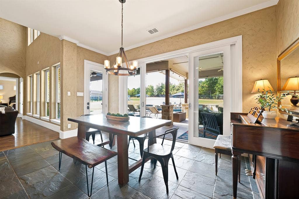Slate tile flooring, patio access, high ceilings, large windows, and a modern chandelier