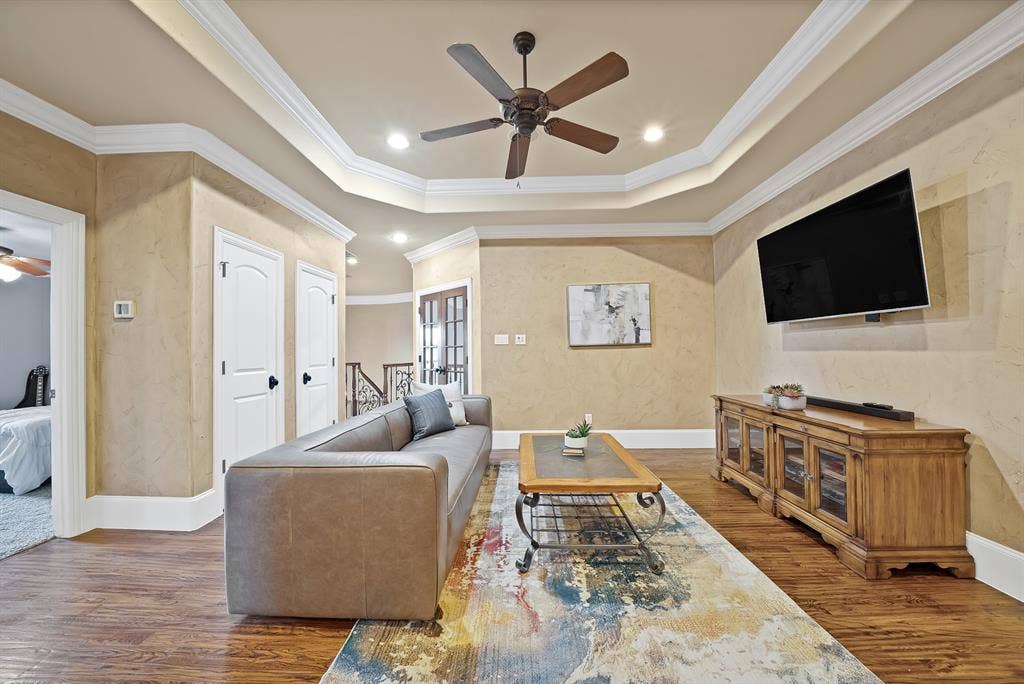 hand scraped hardwood floors, tray ceiling, recessed lighting, ceiling fan, and decorative crown molding